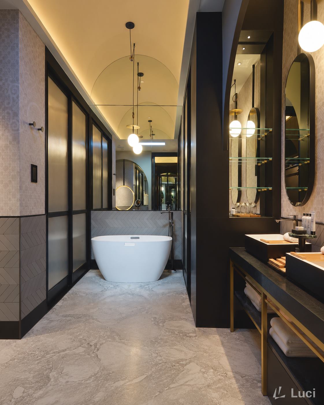 Artyzen Singapore bathroom with a vaulted ceiling lit by concealed cove lighting, opal glass pendants, freestanding tub and stone floor