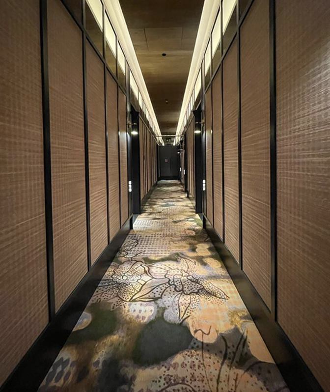Artyzen Singapore guest corridor with woven wall panels and a botanical patterned carpet running the length of the floor