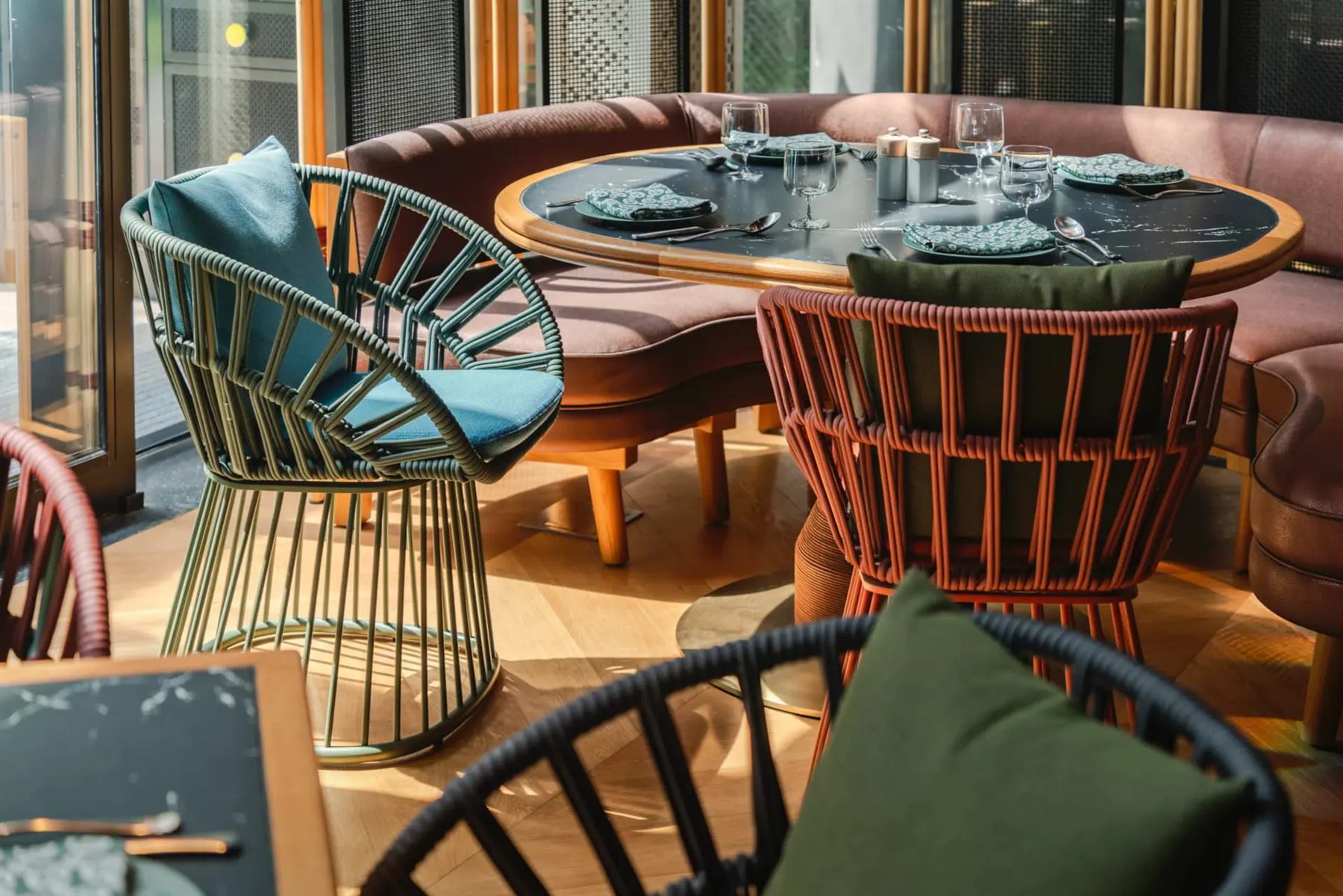 Kettal Cala dining armchairs in woven cord, in sage and terracotta, around a table at Artyzen Singapore
