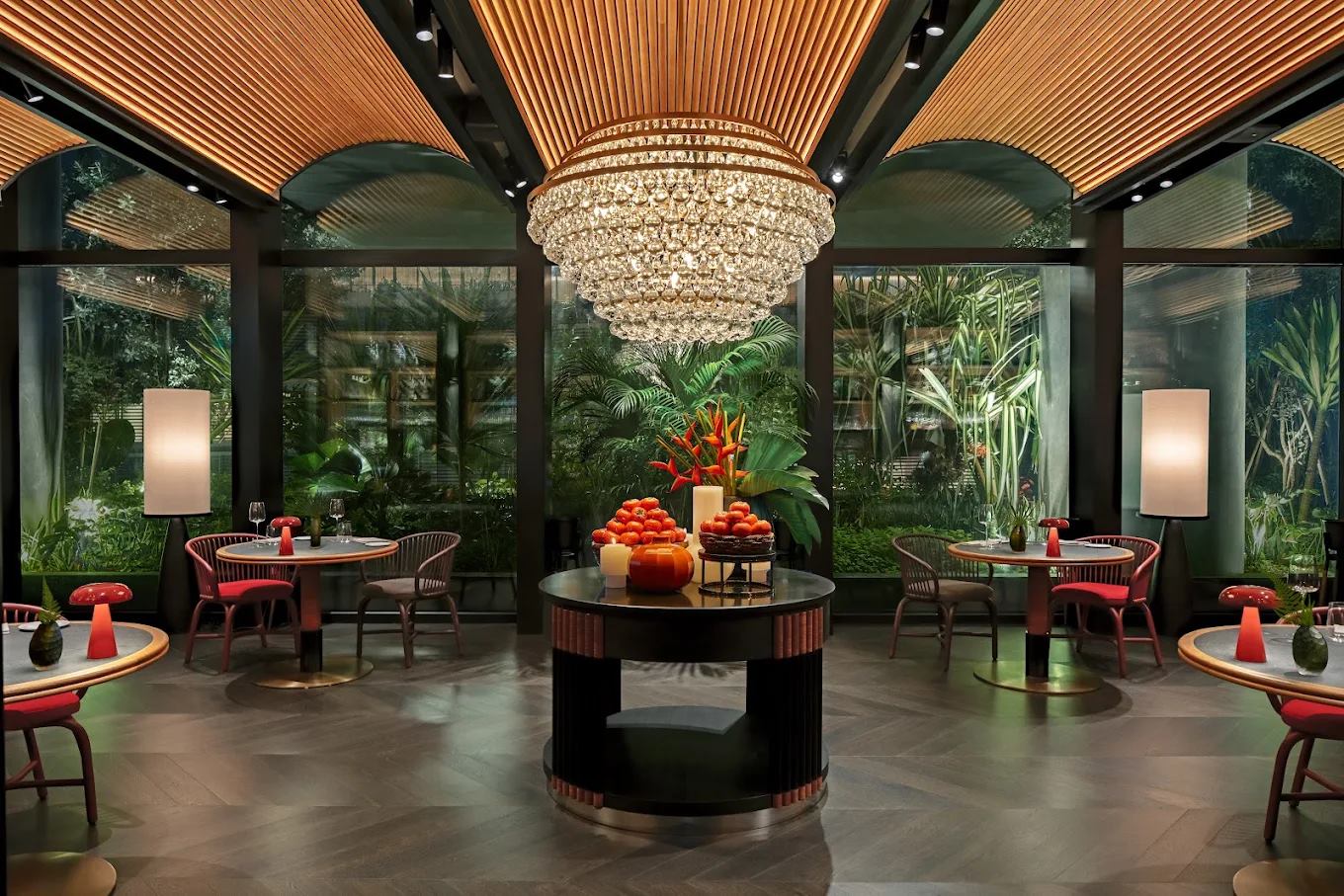 Artyzen Singapore dining room with a fluted timber vaulted ceiling, crystal chandelier, red rattan chairs and windows onto tropical planting