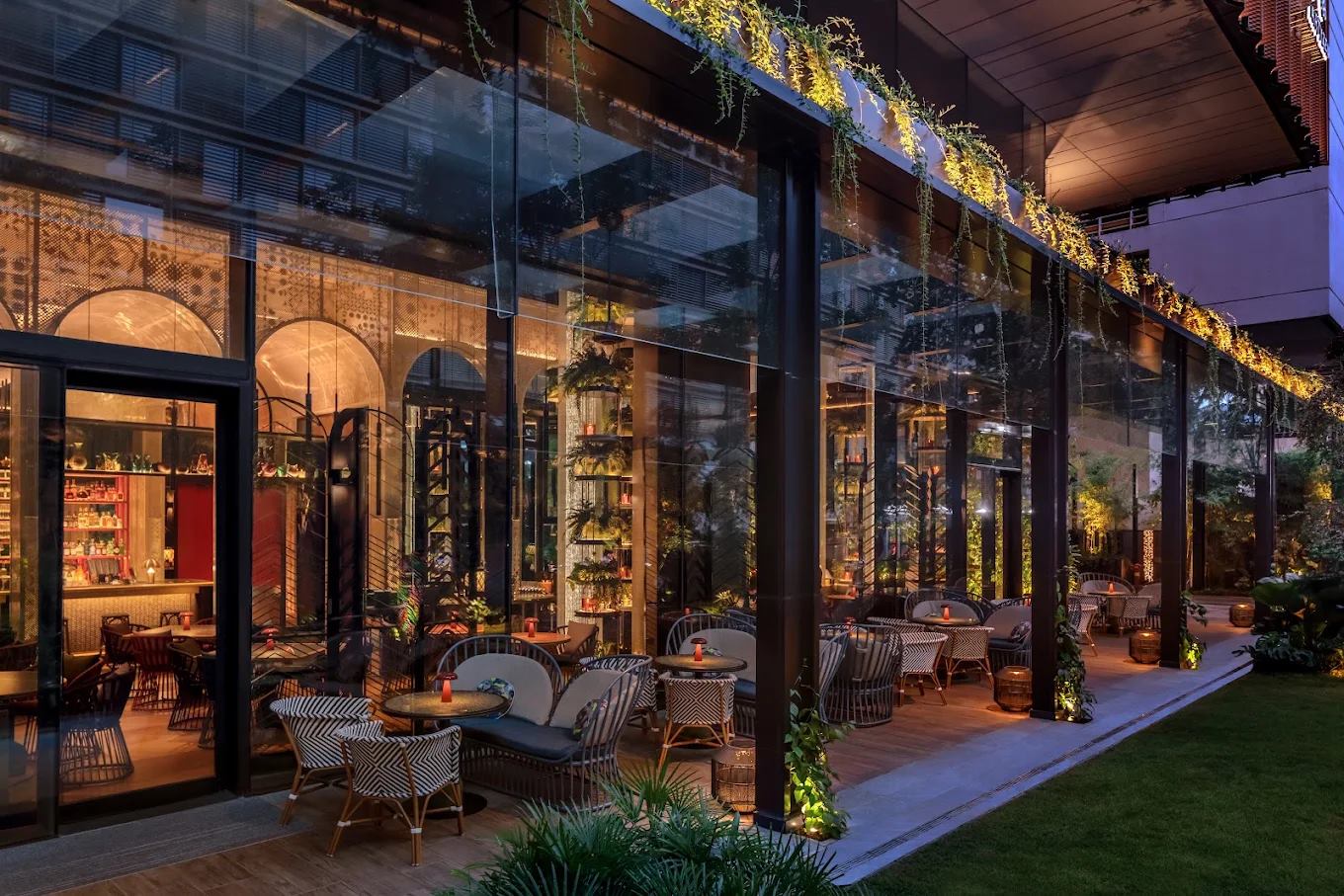 Artyzen Singapore ground-floor bar and garden terrace at dusk with rattan-framed seating