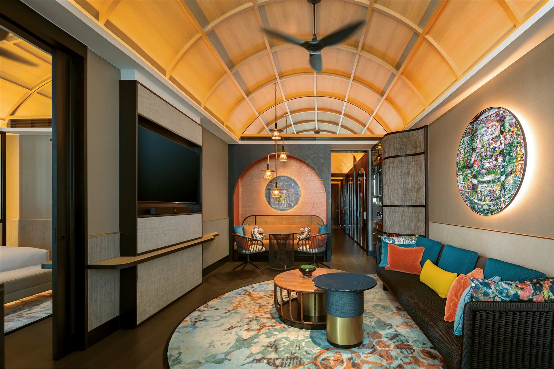 Artyzen Singapore suite living area with a backlit circular artwork, grasscloth wall panels and a vaulted timber ceiling